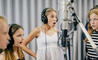 Barn som sjunger i en studio framför mikrofoner